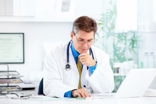 Foto: Arzt sitzt vor Laptop