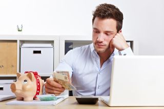 Foto: Mann mit Taschenrechner und Bargeld